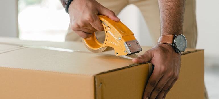A person closing a moving box