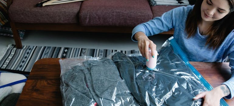 A woman putting seasnonal clothes inside a bag