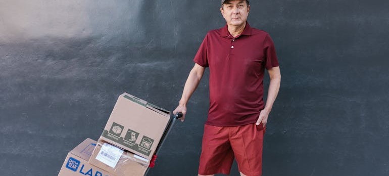 A man holding a dolly with boxes on it after knowing how to safely move large appliances