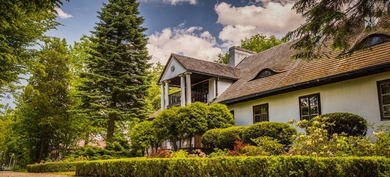 A white house surrounded by trees and bushes showcases how to move into a historic home in Ottawa.