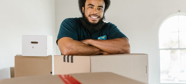 A mover standing beside moving boxes