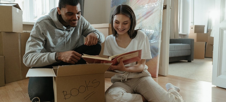 A couple is sitting on the floor and unpacking after the move. 