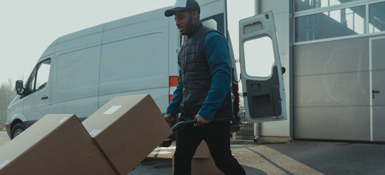 A mover with a dolly unloading boxes from a van