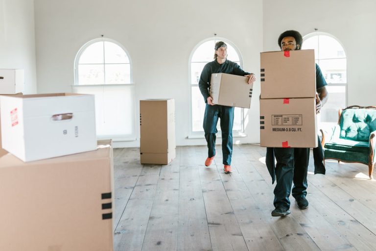 Two men are carrying the boxes inside the house.