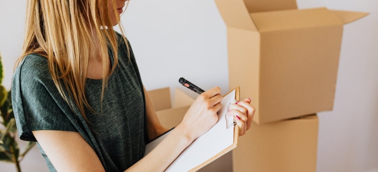 A woman writing on a clipboard, using a checklist to decide which is the best student summer storage in Ottawa