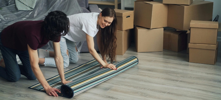 Smiling Woman and Man Putting Carpet on Floor