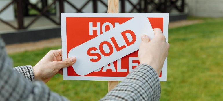 Shallow Focus Photo of a Realtor Posting a Sold Sticke