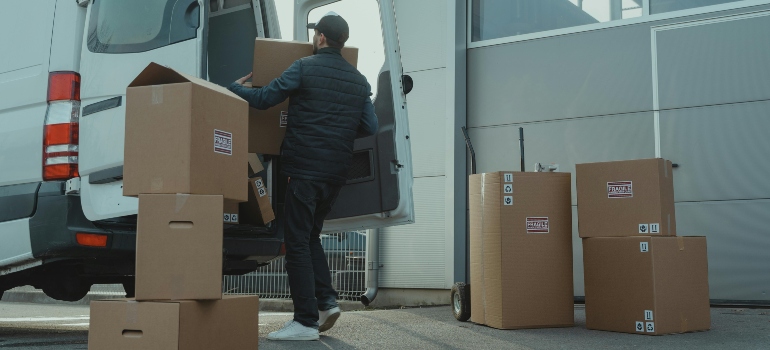 Man in a blue jacket and denim jeans sitting on a cardboard box—showing a common moment during a move and why Ottawa residents need storage between moves.
